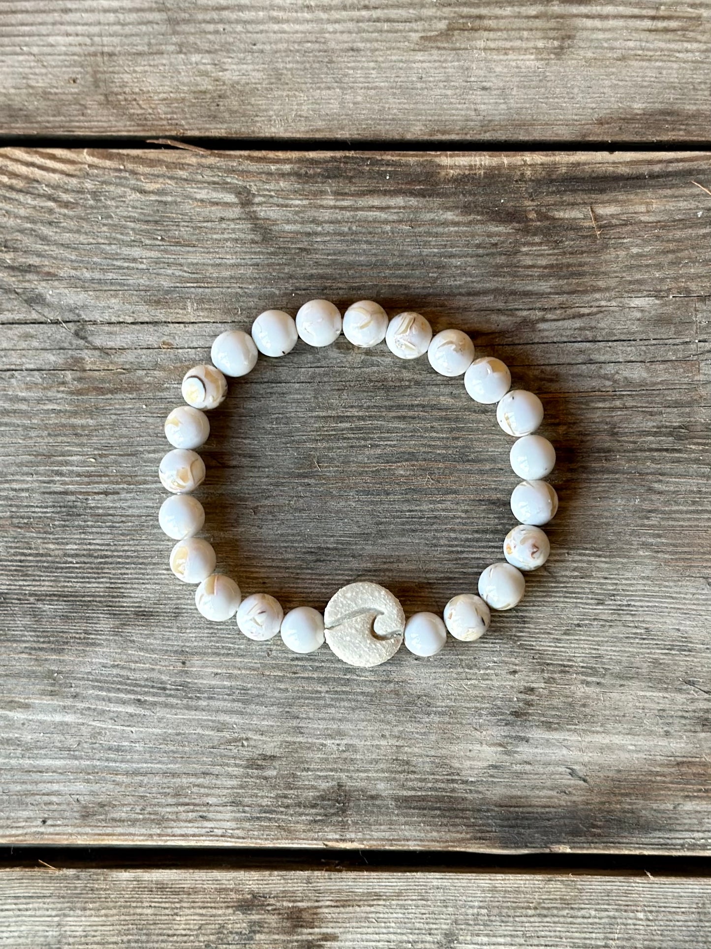 Studio Meraki bacelet with howlite chrystal pearls and a raw ceramic pearl with a wave.