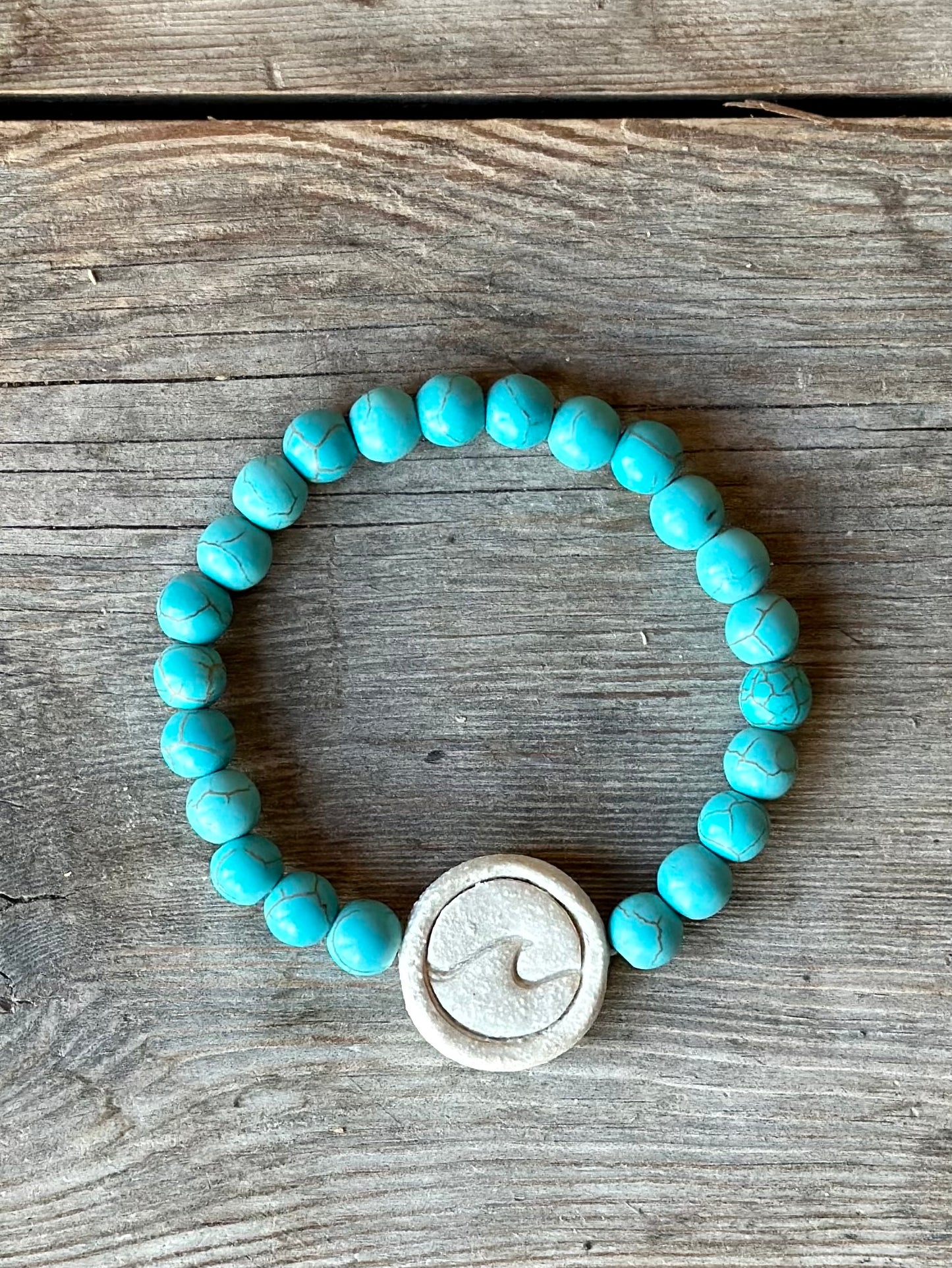 Studio Meraki bacelet with turqoise chrystal pearls and a raw ceramic pearl with a wave.
