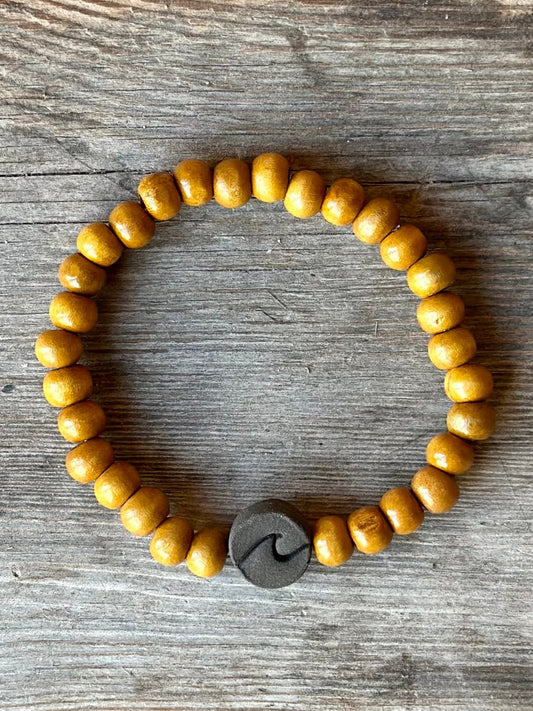 Studio Meraki bacelet with wood pearls and a raw ceramic pearl with a wave.
