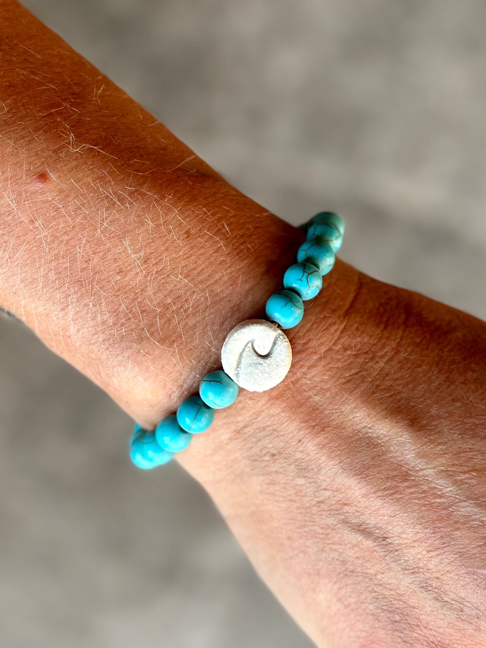 Studio Meraki bacelet with turqoise chrystal pearls and a raw ceramic pearl with a wave.