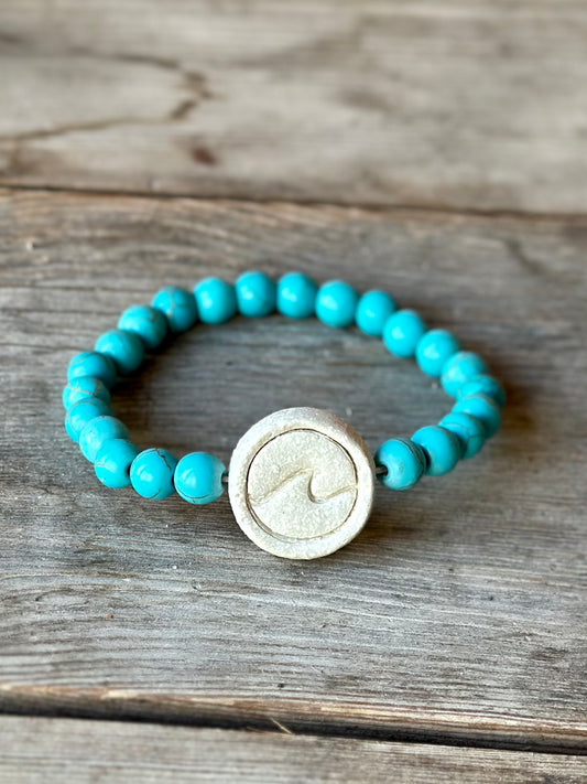 Studio Meraki bacelet with turqoise chrystal pearls and a raw ceramic pearl with a wave.