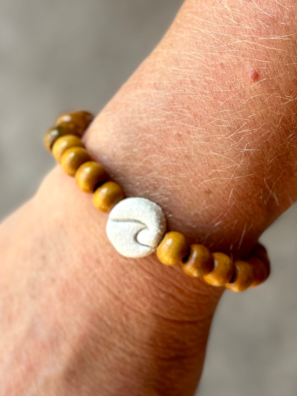 Studio Meraki bacelet with wood pearls and a raw ceramic pearl with a wave.