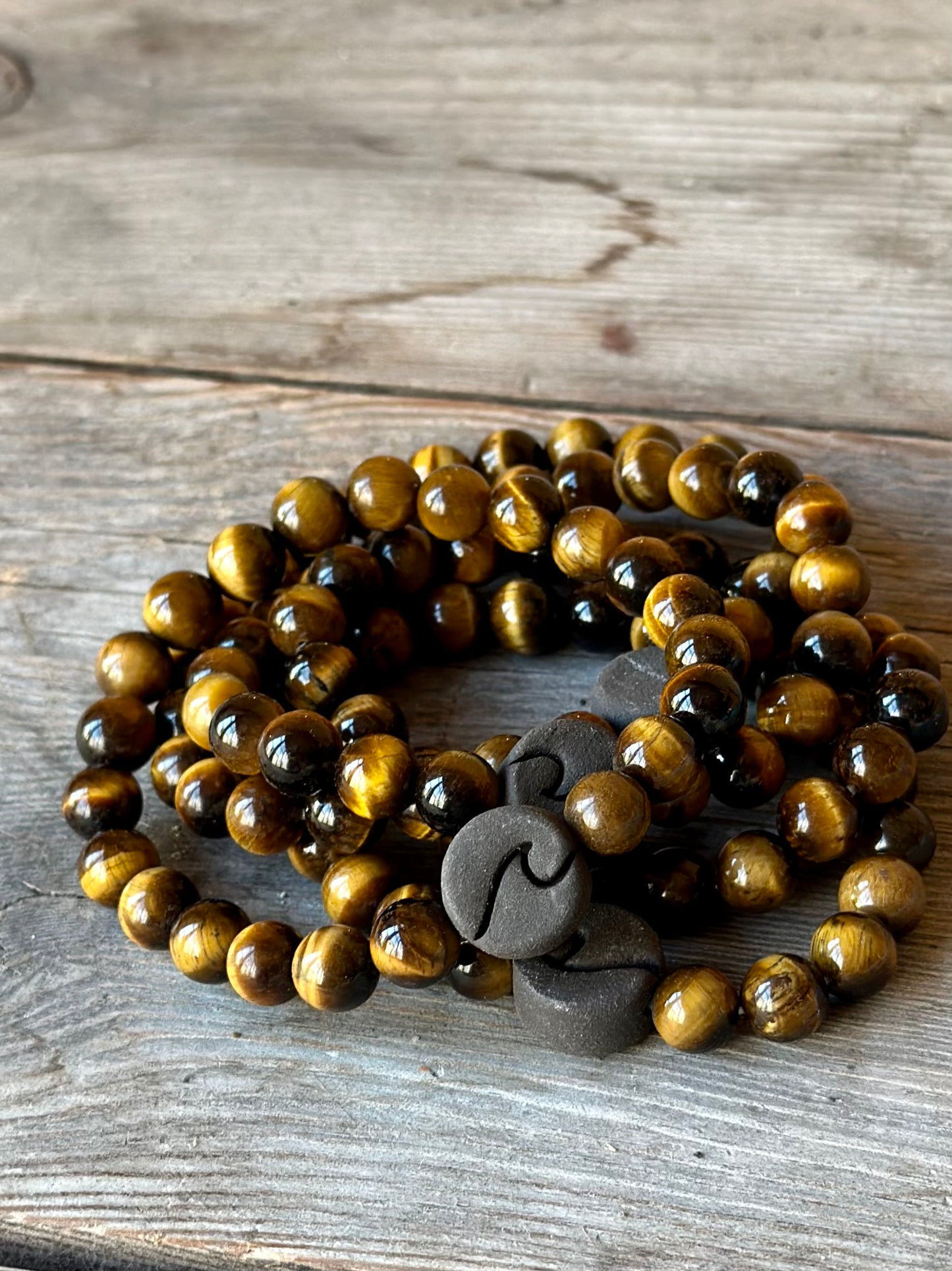 Studio Meraki bacelets with tiger's eye chrystal pearls and a raw ceramic pearl with a wave.