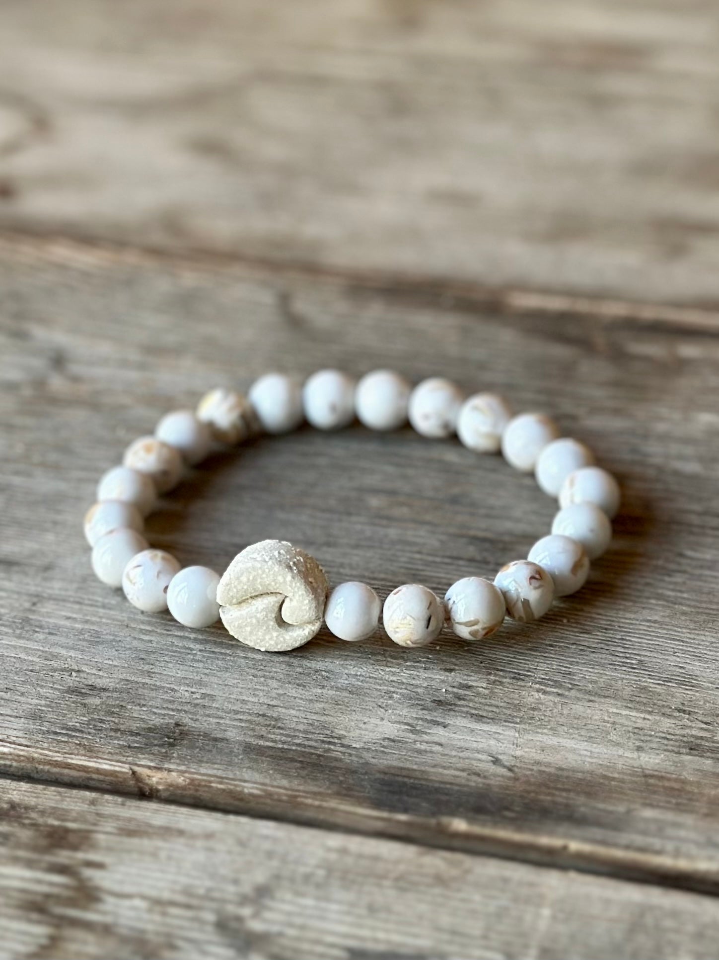 Studio Meraki bacelet with howlite chrystal pearls and a raw ceramic pearl with a wave.
