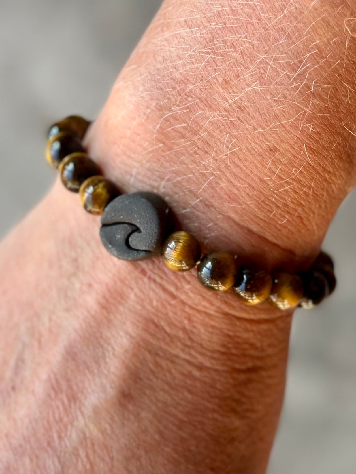 Studio Meraki bacelet with tiger's eye chrystal pearls and a raw ceramic pearl with a wave.