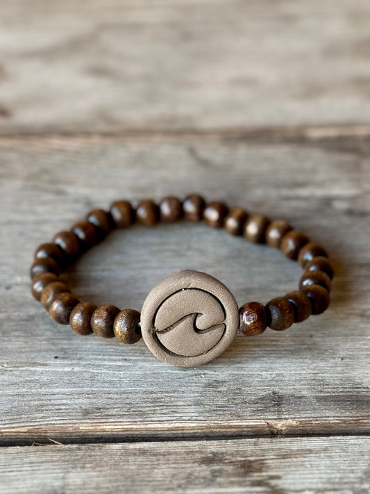 Studio Meraki bacelet with wood pearls and a raw ceramic pearl with a wave.