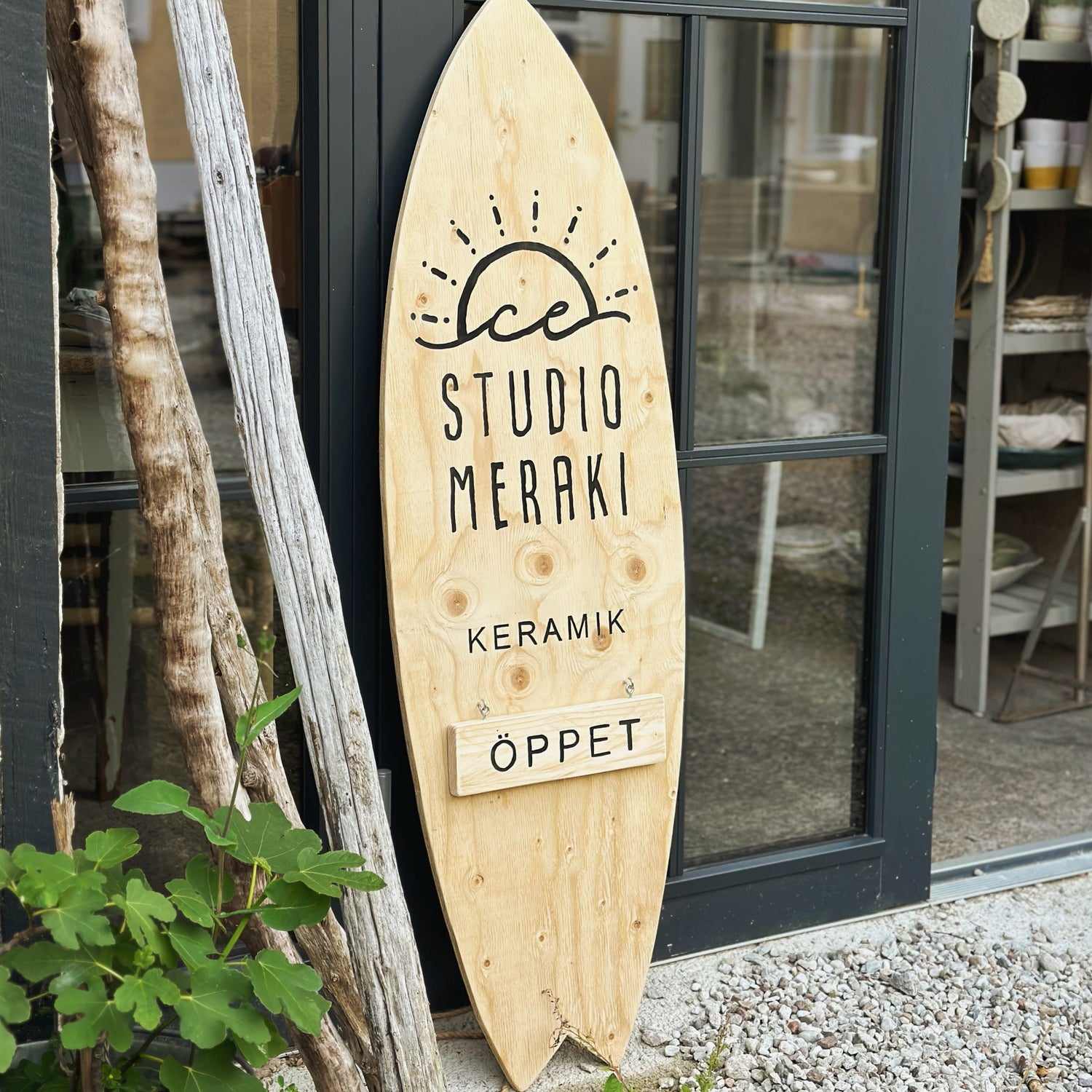 Surfboard shaped sign outside Studio Meraki pottery studio in Visby, Gotland, Sweden, saying: Studio Meraki Ceramics Open