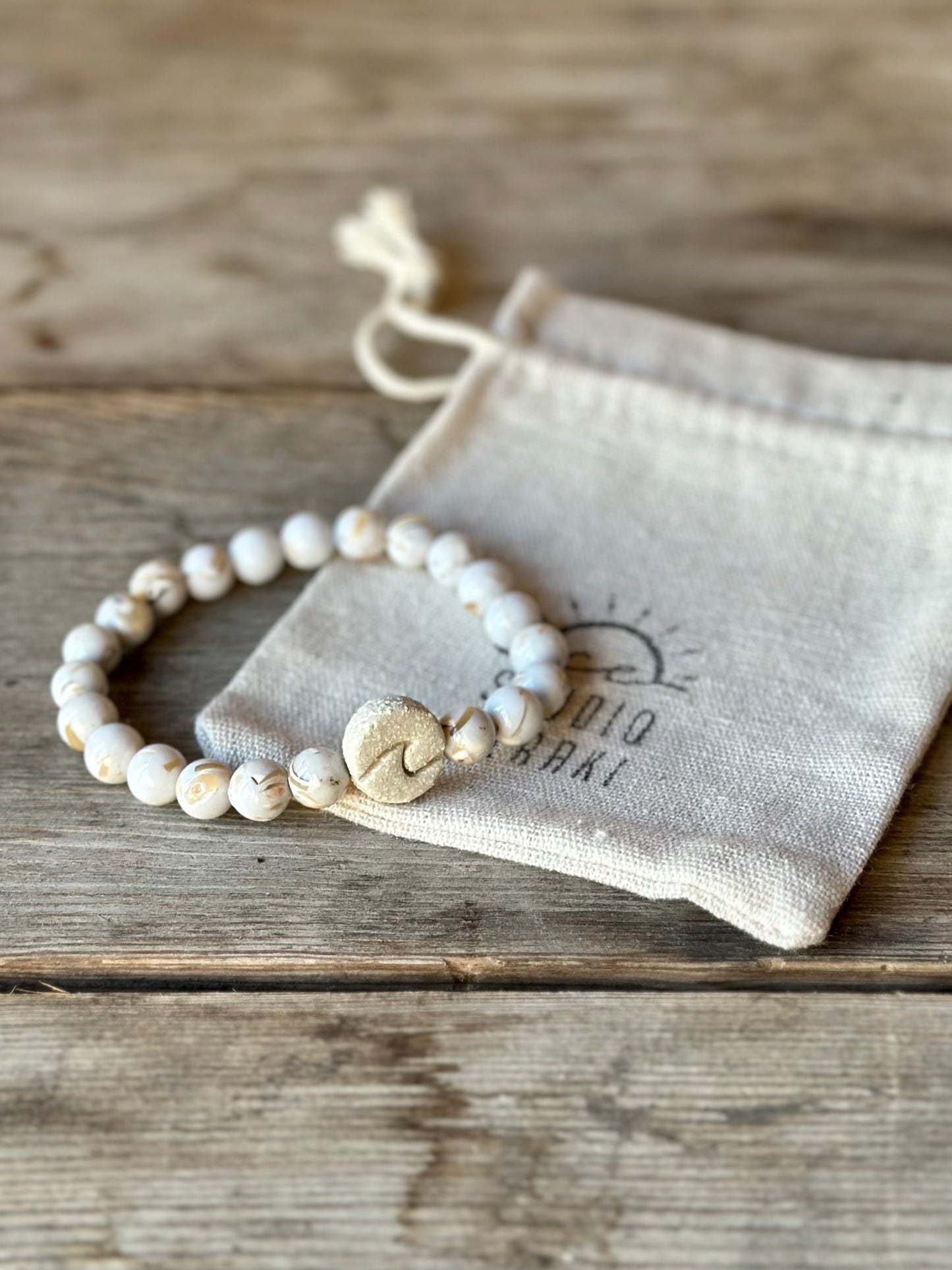 Studio Meraki bacelet with howlite chrystal pearls and a raw ceramic pearl with a wave.