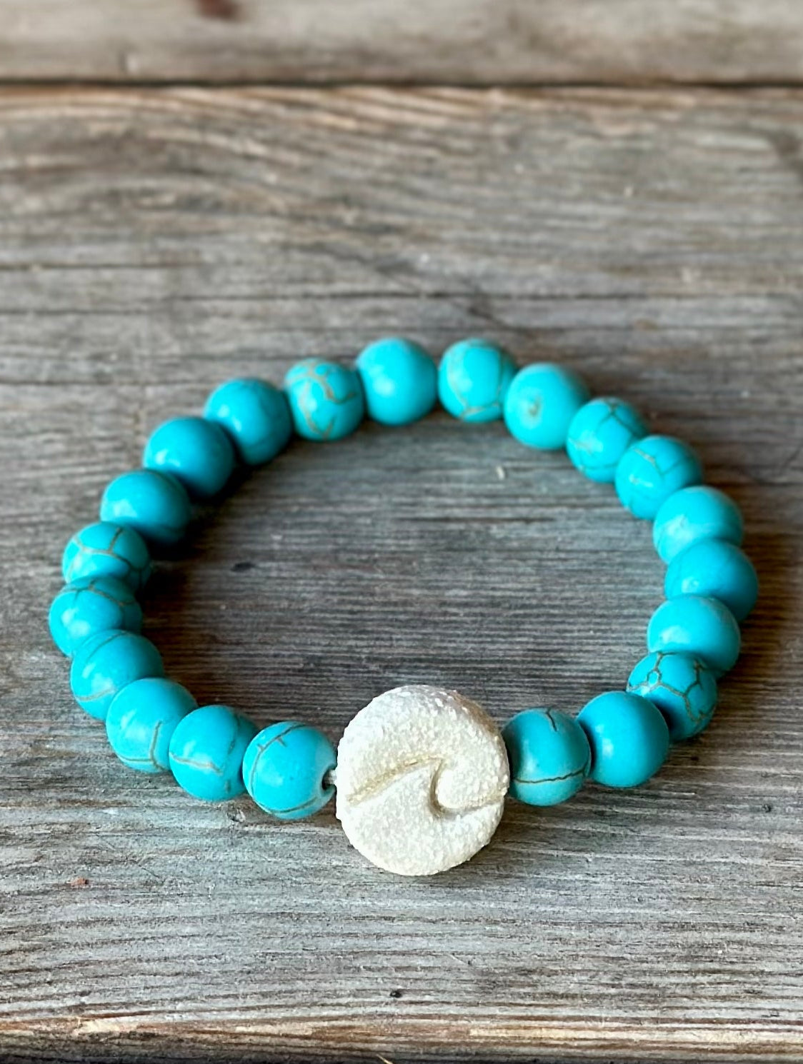 Studio Meraki bacelet with turqoise chrystal pearls and a raw ceramic pearl with a wave.