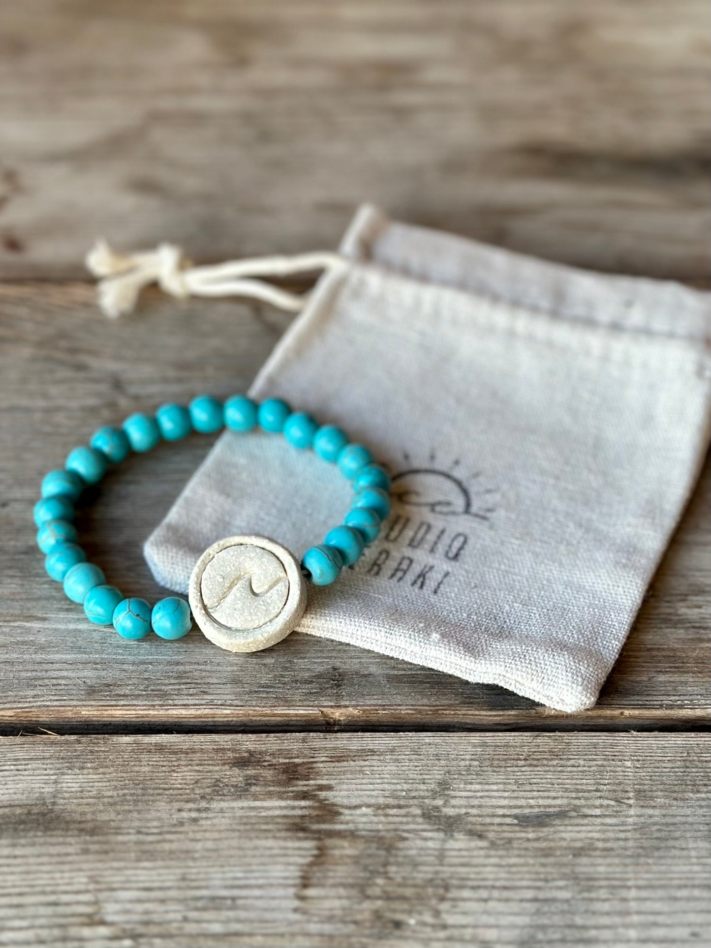 Studio Meraki bacelet with turqoise chrystal pearls and a raw ceramic pearl with a wave.