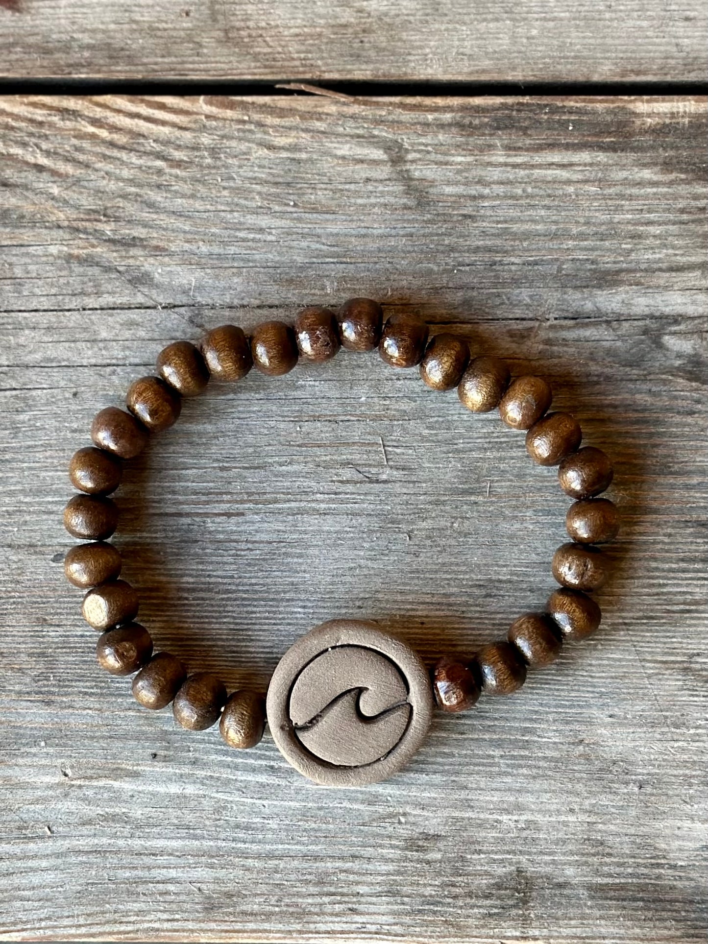Studio Meraki bacelet with wood pearls and a raw ceramic pearl with a wave.