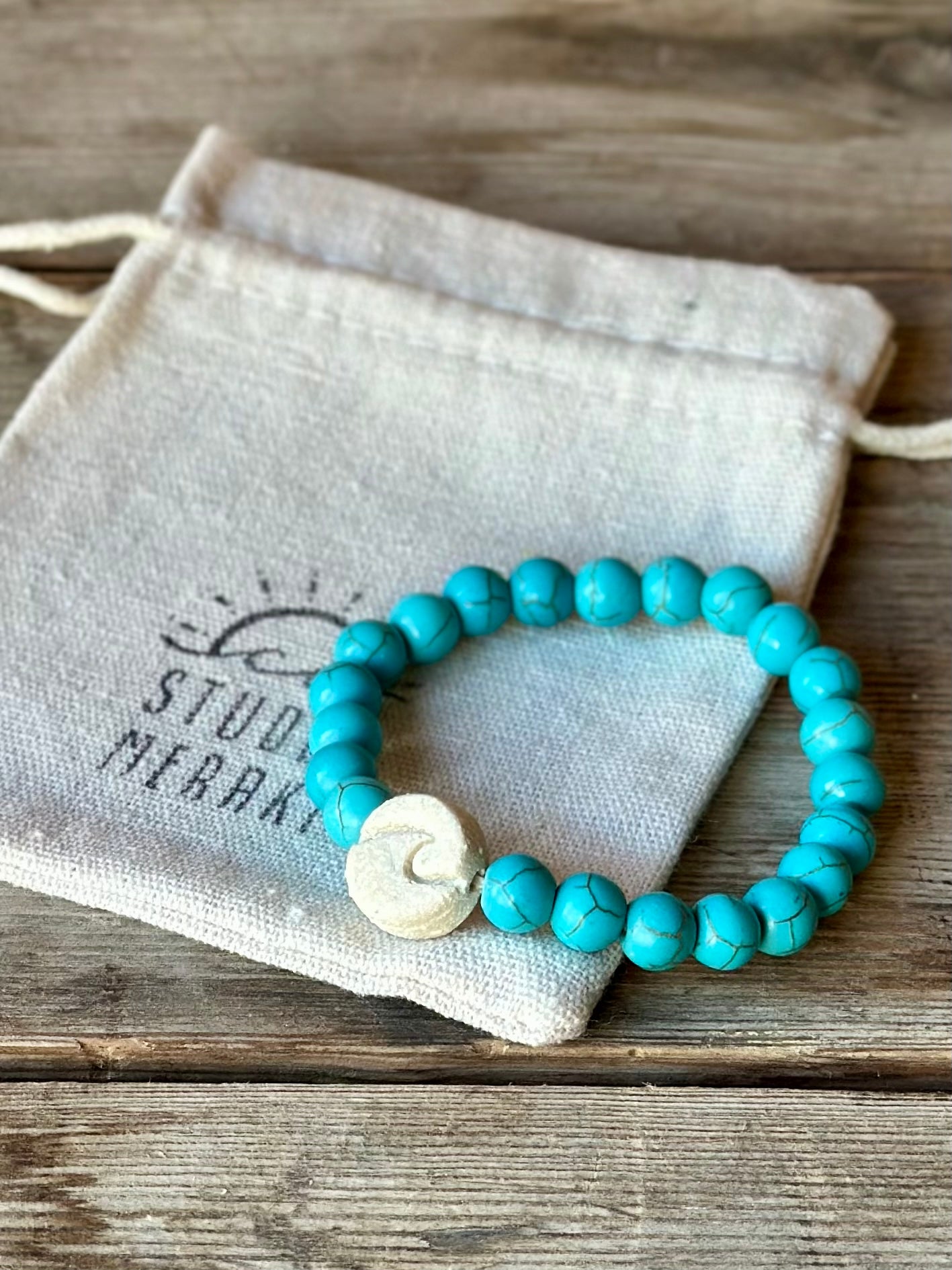 Studio Meraki bacelet with turqoise chrystal pearls and a raw ceramic pearl with a wave.