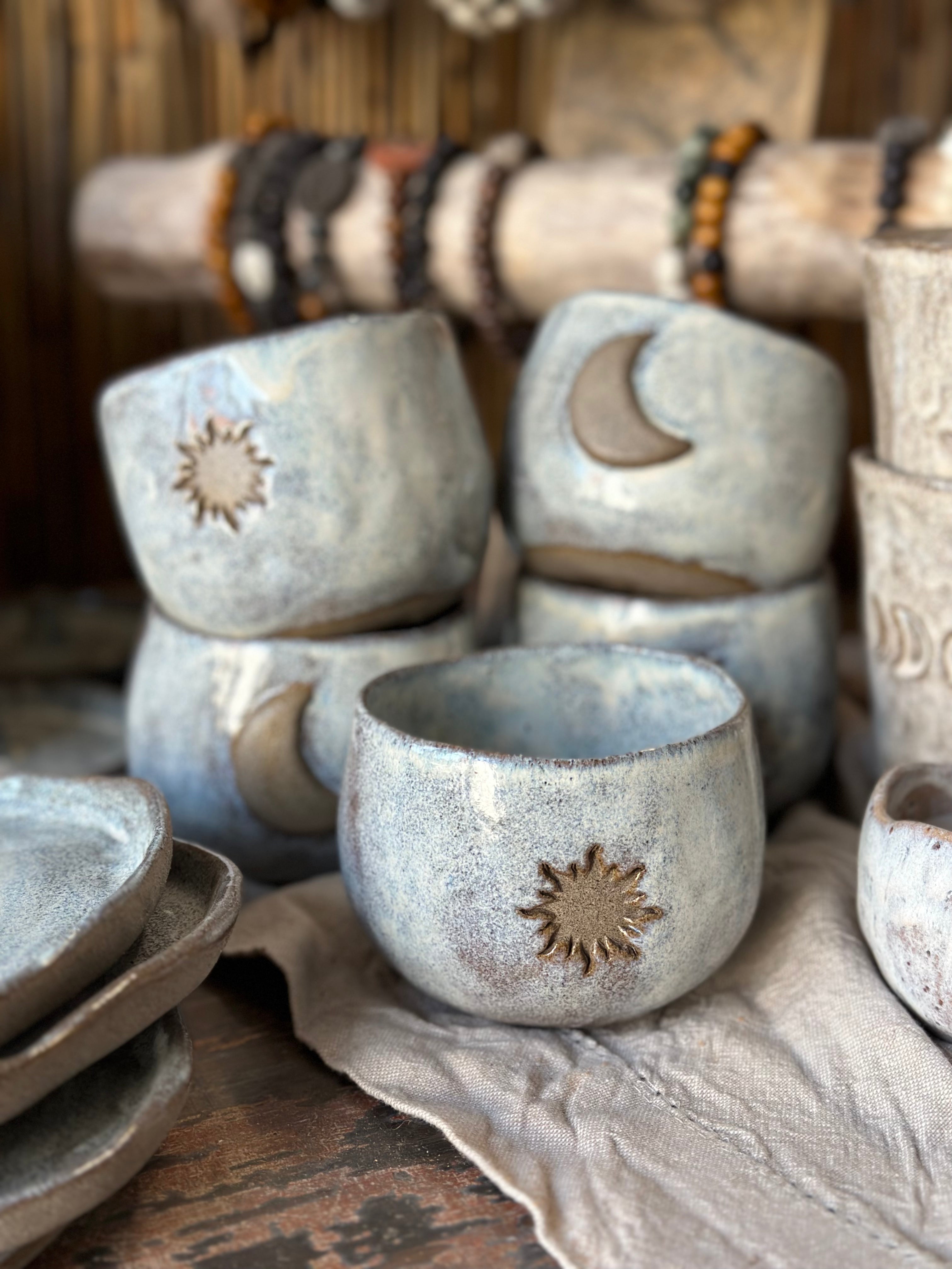 Close up from Studio Meraki ceramic shop, showing ceramic cups decorated with sun and moon.