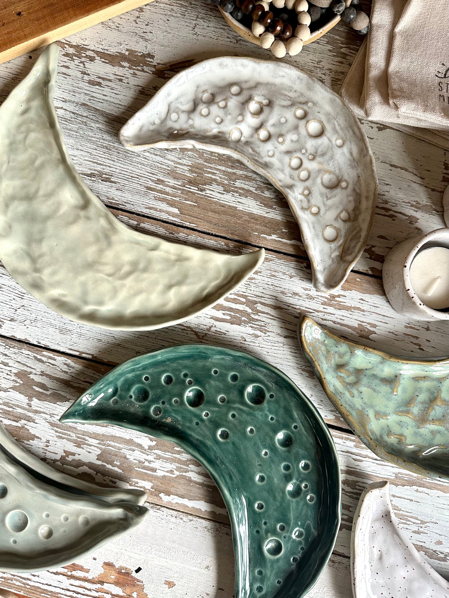 Moon shaped decorative ceramic trays in different glazeson a table.