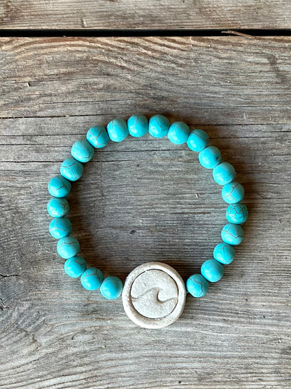 Studio Meraki bacelet with turqoise chrystal pearls and a raw ceramic pearl with a wave. 
