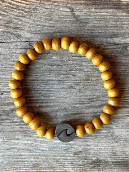 Studio Meraki bacelet with wood pearls and a raw ceramic pearl with a wave. 