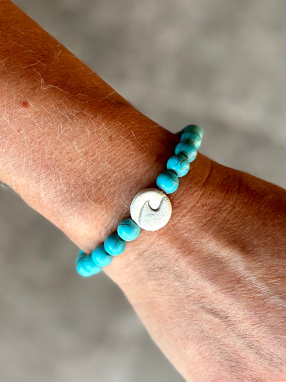 Studio Meraki bacelet with turqoise chrystal pearls and a raw ceramic pearl with a wave. 