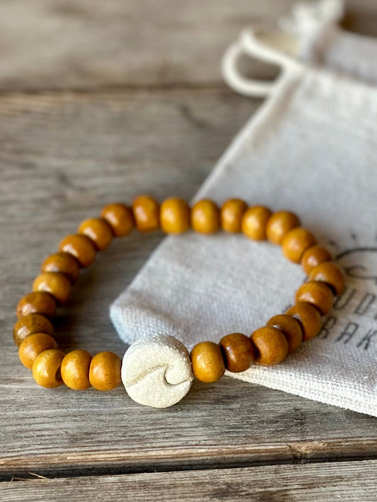 Studio Meraki bacelet with wood pearls and a raw ceramic pearl with a wave. 