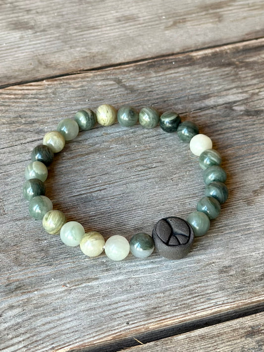 Studio Meraki bacelet with agate chrystal pearls and a raw ceramic pearl with a peace sign. 