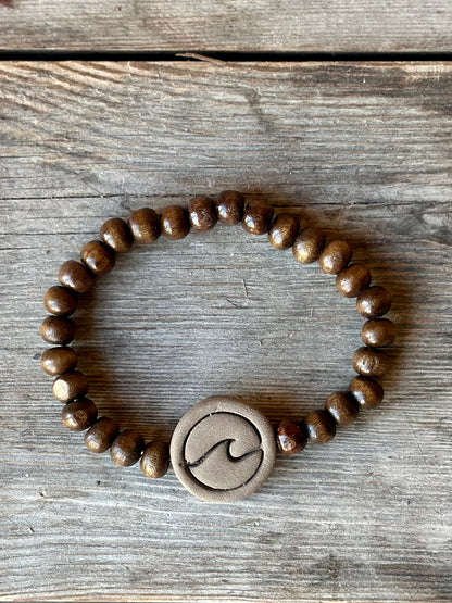 Studio Meraki bacelet with wood pearls and a raw ceramic pearl with a wave. 