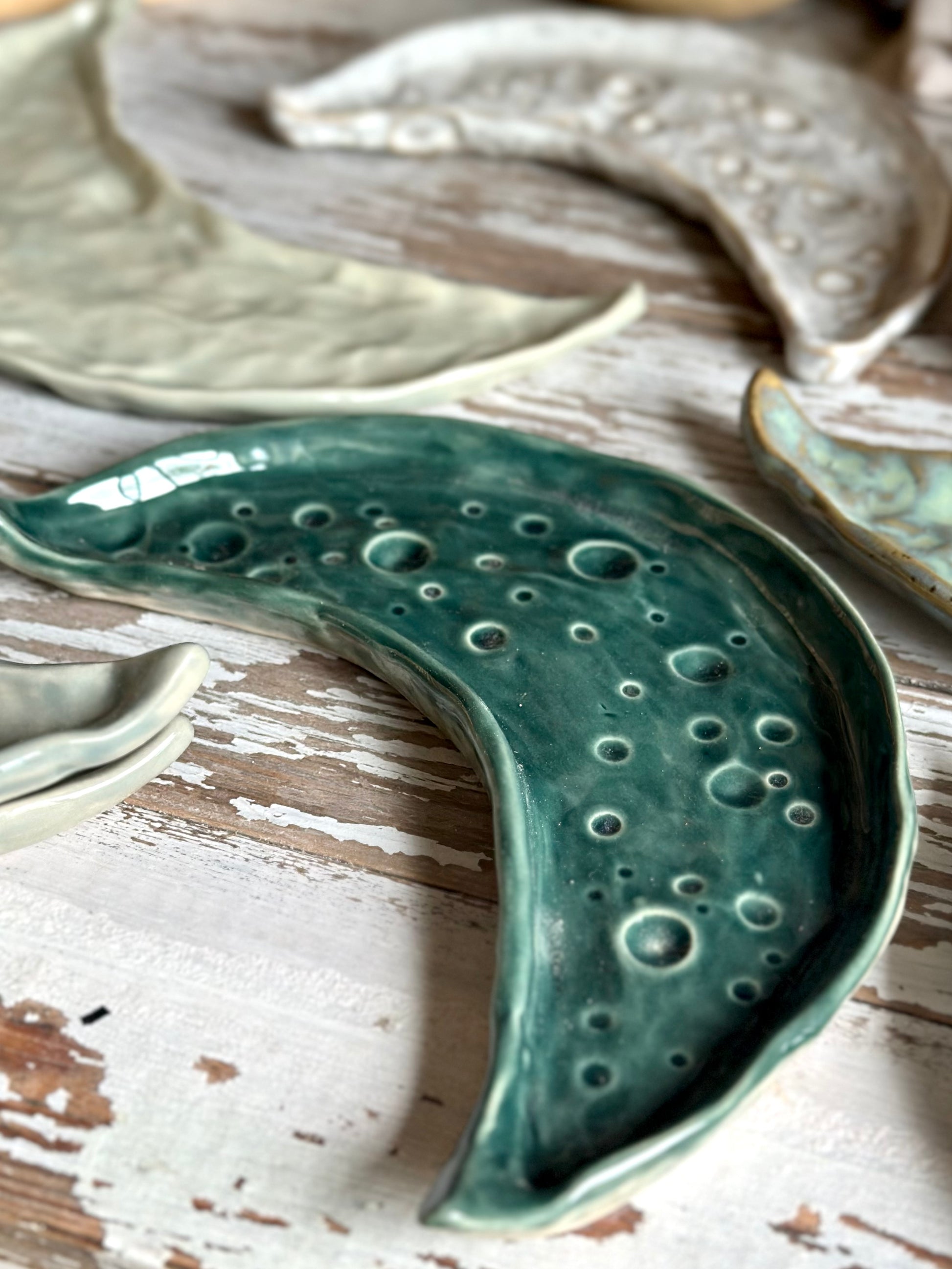 Moon shaped decorative ceramic trays in different colors on a table.