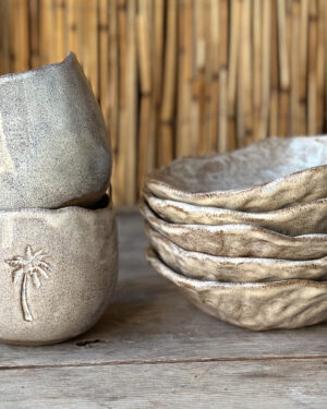 handmade ceramic cups and bowls with a rustic design, palmtree on the side of the cup