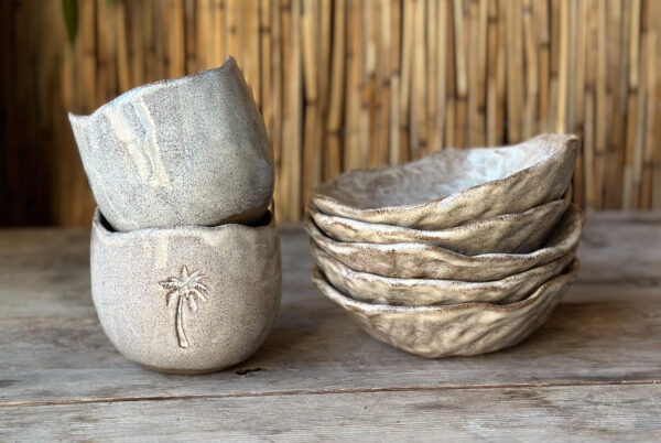 handmade ceramic cups and bowls with a rustic design, palmtree on the side of the cup